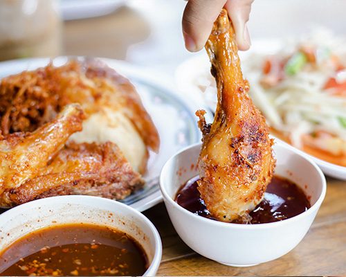 Pessoa colocando frango feito na airfryer em um pote com molho