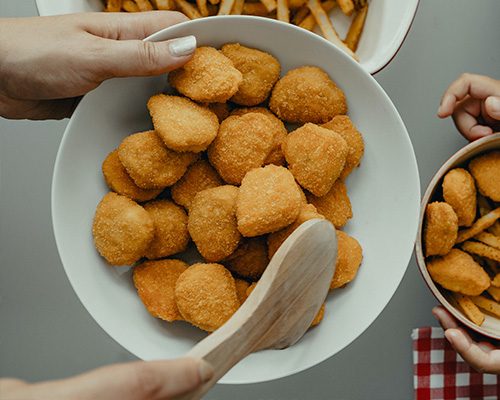 Pessoa segurando uma cesta de salgados feitos na airfryer